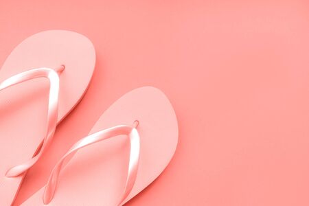 Coral flip flops on a coral background. Color of the year. Place for text.の写真素材