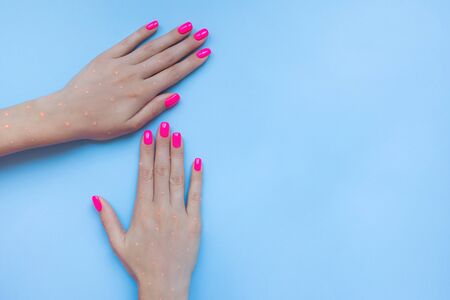 Stylish trendy female manicure. Beautiful neon plastick pink nails on blue background.の写真素材