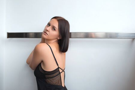 Portrait of a sensual girl in a black nightgown on a light background. Fashion vogue style portrait.の写真素材