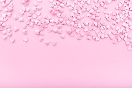 Pink background. Pink hearts on a pink background. Hearts sprinkles. Flat lay style. Top view. Place for design. Sweet background. Confettiの写真素材