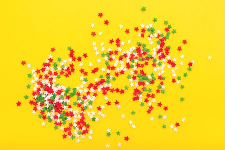 Colorful festive stars sprinkles as a frame on yellow background. Flat lay style. Top view.の写真素材