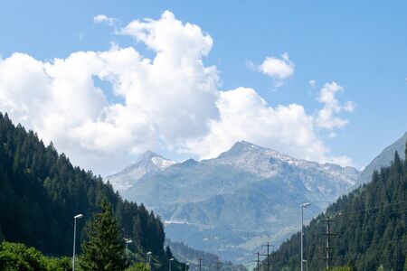 Tree lined vista with mountain range below blue sky with cloudsの写真素材