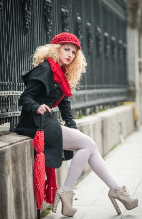 attractive young woman in a winter fashion shot  Beautiful fashionable young girl with red umbrella in the streetの写真素材