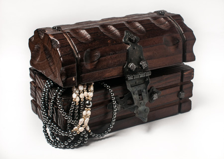 Wooden jewelry box packed with accessories. Wooden treasure trunk with jewelery, isolated on white. Treasure chest with jewelryの写真素材