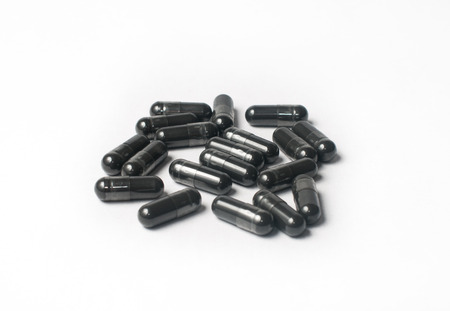 Activated carbon in capsule isolated on whiteの写真素材