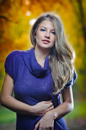 Beautiful elegant woman standing in a park in autumn.Young pretty woman at the autumn park. Attractive woman spending time in park during autumn seasonの写真素材