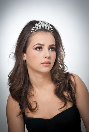 Hairstyle and make up - beautiful female art portrait with beautiful eyes. Genuine natural brunette with jewelry, studio shot. Portrait of a attractive woman with tiara and creative make upの写真素材
