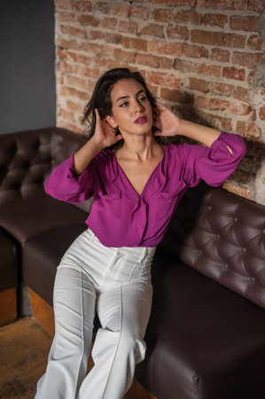 Beautiful brunette woman in a purple blouse and white pantsの写真素材