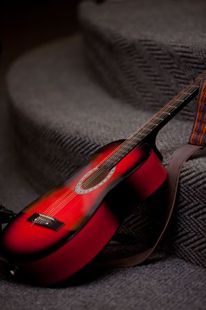 Red Guitar with strap left on grey staircaseの写真素材