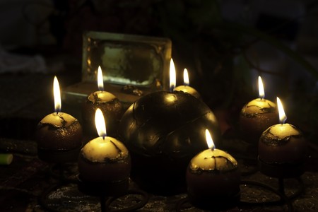 a collection of candles arranges around a bigger candle burning with soft lightの写真素材