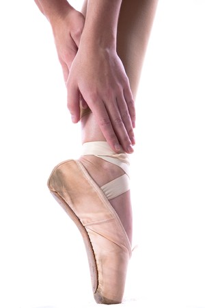young Caucasian girl in ballet slippers standing on one pointed toe stretching hands to feetの写真素材