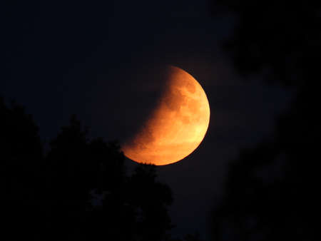 Early evening moon glowing orange through the earths elongated atmosphere
