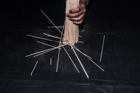 Spaghetti, pasta Italian on black background. Great food, bronze drawing, lying down, fallen, star, grasped by the hand, the hands of men.の写真素材