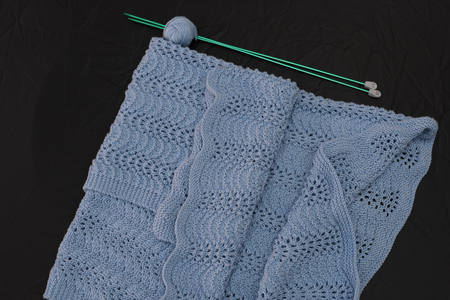 Cover hand knitted wool with knitting needles. blue on white or black background.