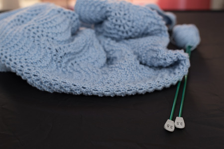 Cover hand knitted wool with knitting needles. blue on white or black background.