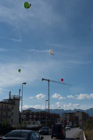 White heelium ballons, red and green, attached to wire in a blue skyの写真素材