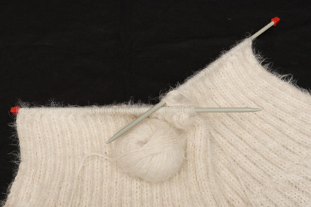Create a mesh of white, hairy wool with knitting needlse.