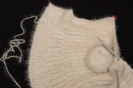 Create a mesh of white, hairy wool with knitting needlse.