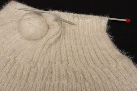 Create a mesh of white, hairy wool with knitting needlse.