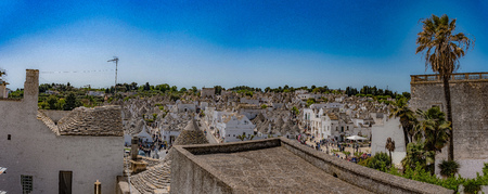 Alberobello, Puglia, Italy, Murge, view of the ancient peasant village. White trulets crowding people in the background on the blue sky.の写真素材