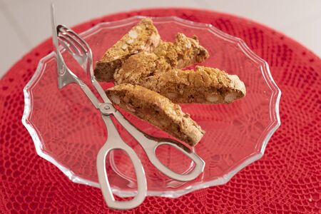 Four Cantucci on glass tray, typical of the Italian tradition. Red crochet tablecloth. Ready to be served.の写真素材