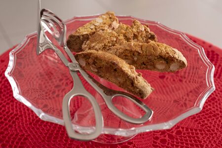 Four Cantucci on glass tray, typical of the Italian tradition. Red crochet tablecloth. Ready to be served.の写真素材