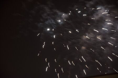 Fire stars, plays of light, clouds of smoke in the black sky of a summer night.の写真素材