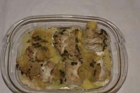 Baked cod with yellow potatoes and aromatic herbs in bread crust. Italian recipe. Details.の写真素材