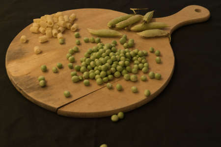 Peas, beans on wooden chopping board on a black background. Ingredients for pasta and peas. Italian food, Italian style.の写真素材