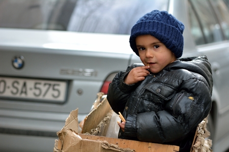 BAKU, AZERBAIJAN - JANUARY 24 2014 Boy in a box in Baku. A young boy travels in a box on his father's trailer, as the parent collects metal and bottles to sell for recyclingのeditorial素材