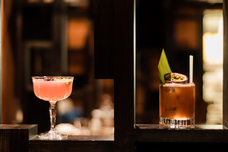 Pink and yellow cocktails garnished with fig and flowers. Alcoholic drinks in bar, in margarita and old fashioned glassesの写真素材