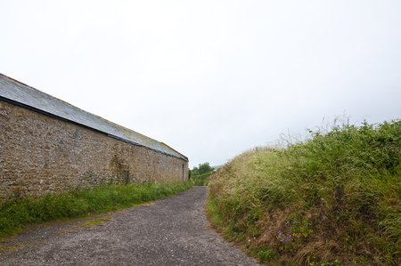 deserted country lane beside a farm buildingの写真素材