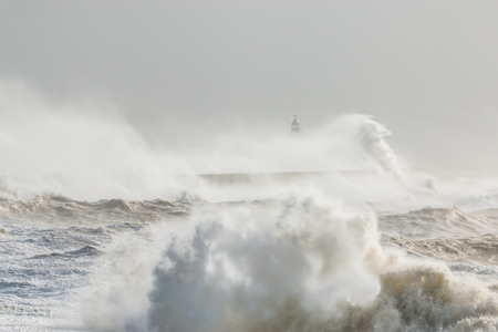 Newhaven, Sussex. Stormy Seas With Waves Crashing against Sea Wall. Lighthouse Partially Visible Behind. Wave Breaking in Foregroundの写真素材