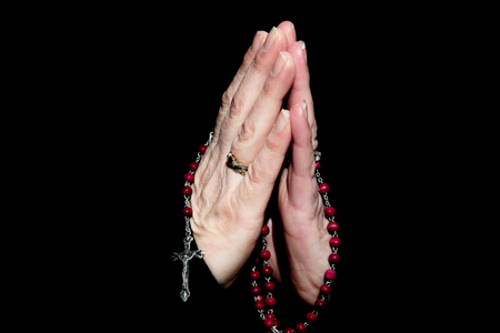 Females Hands  Praying While Holding Rosary Beads.  Isolated on Black