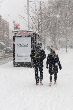 London, UK; 28th February 2018; Rear View of Man and Woman Walking Side by Side During Heavy Snowstormのeditorial素材