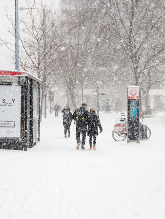 London, UK; 28th February 2018; Rear View of Man and Woman Walking Side by Side During Heavy Snowstormのeditorial素材
