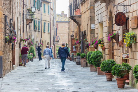 Pienza, Italy; 8th May 2018; Street Scene, Several People Walk Away From the Camera Down a Narrow Pretty Street.のeditorial素材