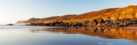 Panoramic shot of Combesgate Beach near Woolacombe Devon with Morte Point relfected in the Sand.