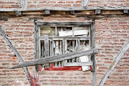 Boarded up window and grungy brick wall. Abandoned house detail