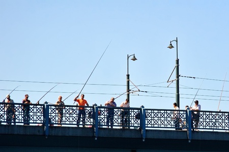 ISTANBUL - SEPTEMBER 02: Fishers wait to catch fish on old Galata Bridge on September 2, 2009 in Istanbul, Turkey. The fishing contributes a significant income to people hereのeditorial素材