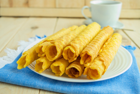 Freshly honey waffles rolled up into tubes on a blue napkin