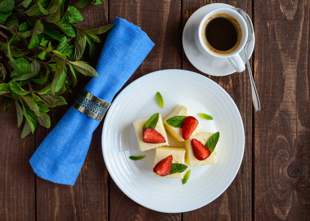 Delicate cottage cheese and creamy souffle in the form of cubes, decorating with mint leaves and fresh strawberries on a white plate.の写真素材