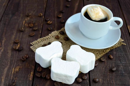 A cup of black coffee  and sweet marshmallow on a dark wooden background. Close upの写真素材