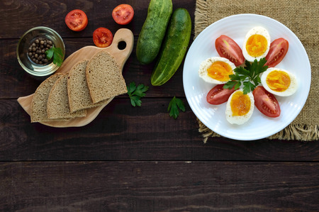 Boiled egg and fresh tomato, black bread - light diet breakfast. The top view