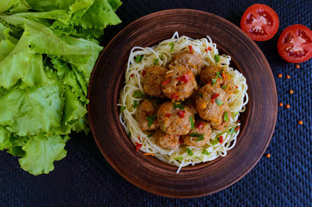 Pasta (spaghetti) with meat balls in a clay bowl on a dark background. The top view.の写真素材