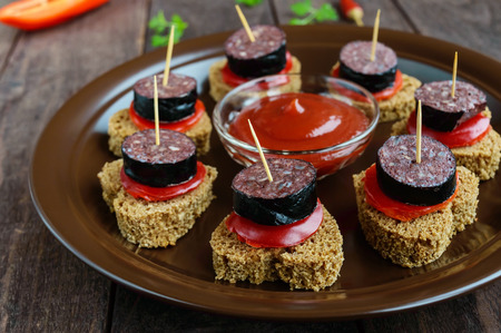 Sandwiches with black rye bread in the shape of a heart, blood sausage (Morcillo) and pieces of...