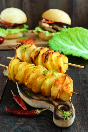 Baked potato circles on a bamboo skewer with spices (homemade chips). Snacks for beer on a dark wooden background.の写真素材