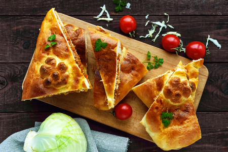 Homemade pie with cabbage chopped pieces on a dark wooden background. The top viewの写真素材