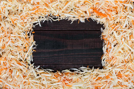 Frame made of salad. Fresh chopped cabbage and carrots. In the middle of a dark wooden space for your notes. Healthy food concept. Lenten menu.の写真素材