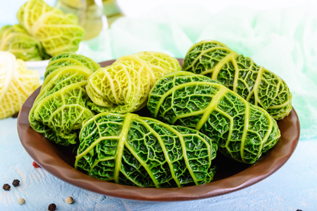 Leaves of Savoy cabbage stuffed with minced meat and rice in a clay bowl on a light background.の写真素材